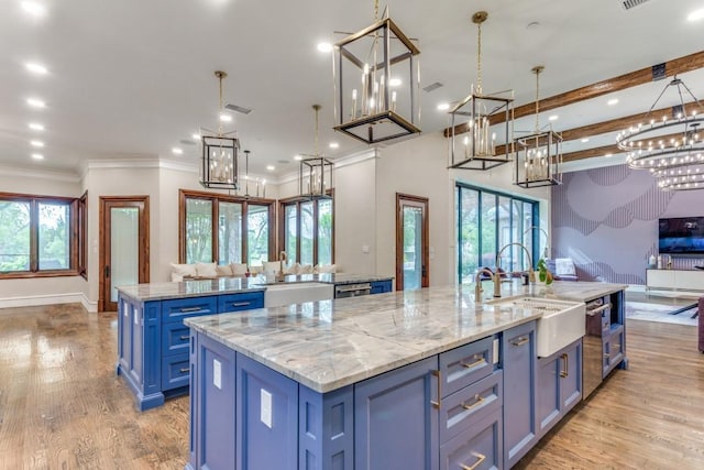 7212 John Mccain Rd, Colleyville, TX 76034 - kitchen featuring a large island with sink, blue cabinets, open floor plan, a sink, and crown molding