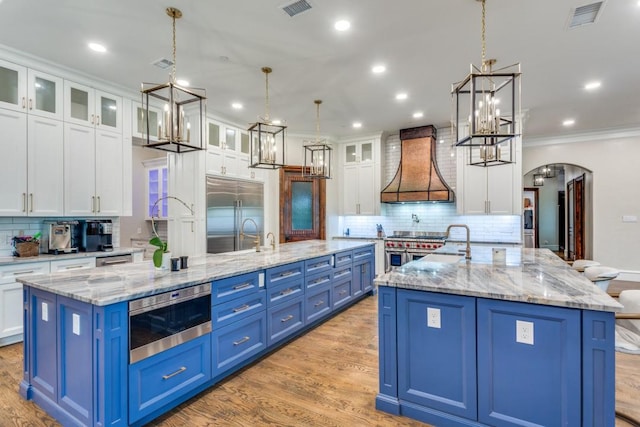 7212 John Mccain Rd, Colleyville, TX 76034 - kitchen with a spacious island, high end appliances, custom range hood, blue cabinetry, and crown molding