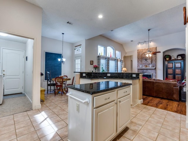 3214 Pecan Meadow Dr, Garland, TX 75040 - kitchen with a kitchen island, light tile patterned floors, open floor plan, decorative light fixtures, and a brick fireplace