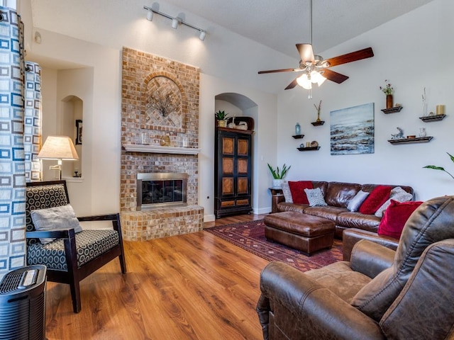 3214 Pecan Meadow Dr, Garland, TX 75040 - living room with arched walkways, a ceiling fan, wood finished floors, a brick fireplace, and vaulted ceiling