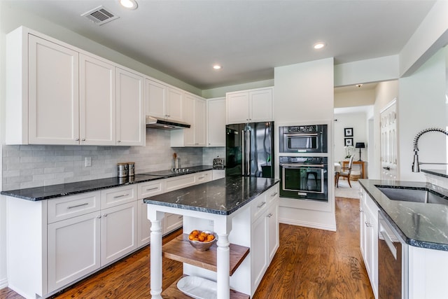 kitchen with black appliances, a sink, under cabinet range hood, a kitchen island, and recessed lighting
