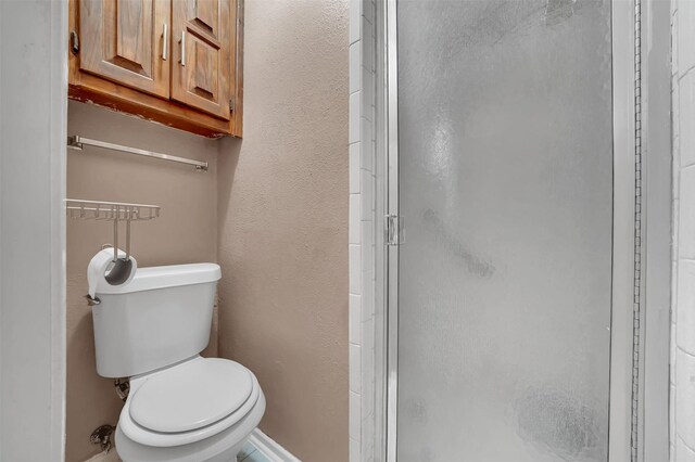 1717 Melrose St, Garland, TX 75042 - bathroom with a shower stall, toilet, a textured wall, and baseboards