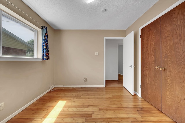 1717 Melrose St, Garland, TX 75042 - unfurnished bedroom with a textured ceiling, light wood finished floors, baseboards, and a closet