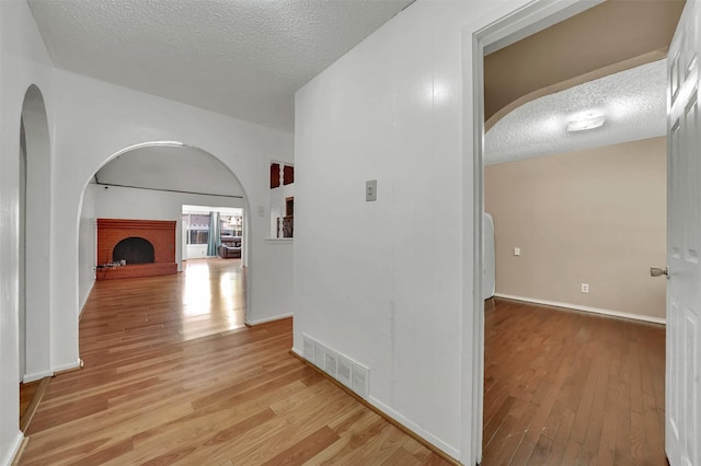 1717 Melrose St, Garland, TX 75042 - corridor with arched walkways, light wood-style floors, a textured ceiling, and baseboards