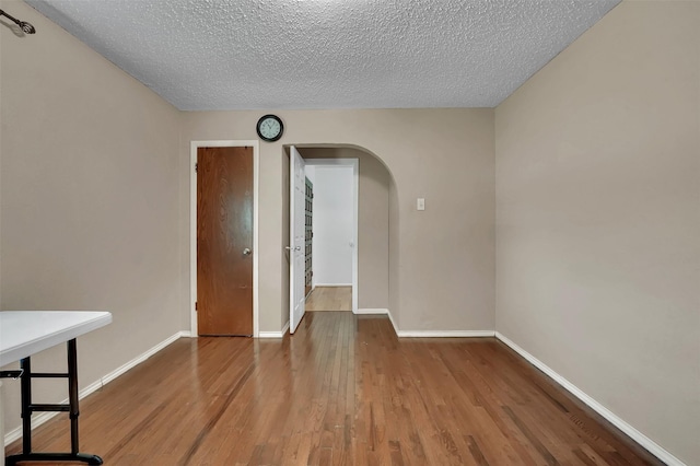 1717 Melrose St, Garland, TX 75042 - empty room with arched walkways, wood finished floors, a textured ceiling, and baseboards