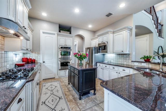 13348 Torrington Dr, Frisco, TX 75035 - kitchen featuring appliances with stainless steel finishes, arched walkways, a sink, decorative backsplash, and dark stone countertops