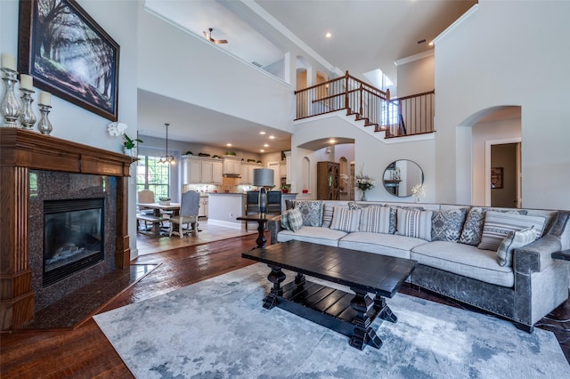 13348 Torrington Dr, Frisco, TX 75035 - living room featuring hardwood / wood-style floors, a towering ceiling, ornamental molding, arched walkways, and a premium fireplace