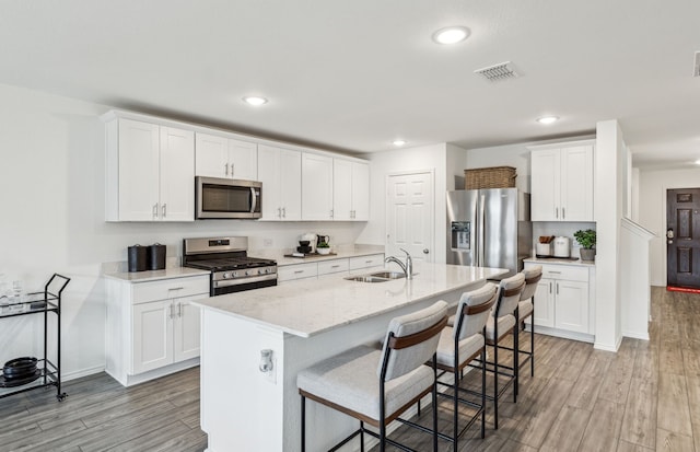 2908 Pecan Park Dr, Denton, TX 76208 - kitchen with appliances with stainless steel finishes, a sink, light wood-style floors, a kitchen breakfast bar, and recessed lighting