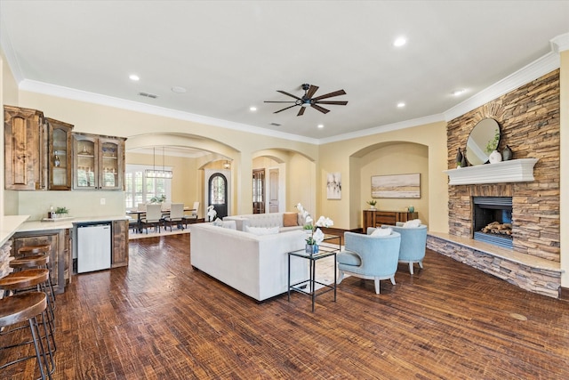 1085 Forest Bend Ct, Cross Roads, TX 76227 - living area with arched walkways, a ceiling fan, a fireplace, dark wood-style flooring, and crown molding