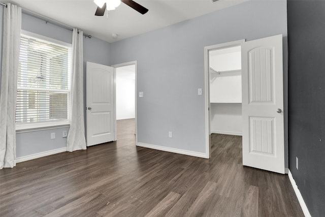 421 E Shepherd St, Denison, TX 75021 - unfurnished bedroom featuring dark wood-style flooring, multiple windows, a walk in closet, and baseboards