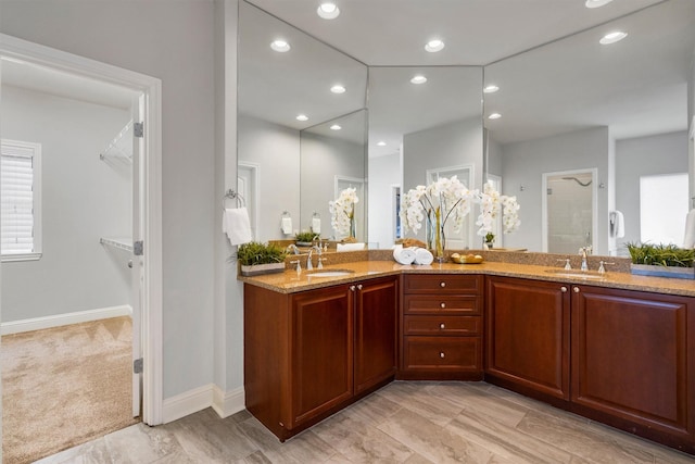 bathroom featuring a shower, double vanity, baseboards, and recessed lighting