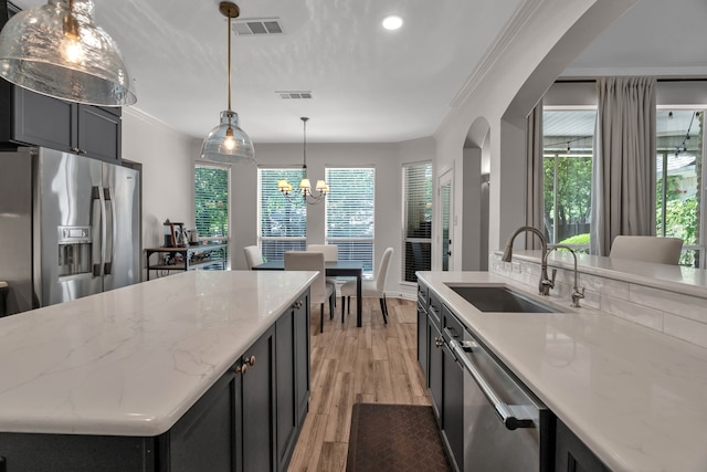 kitchen featuring appliances with stainless steel finishes, a sink, light wood-type flooring, a chandelier, and pendant lighting