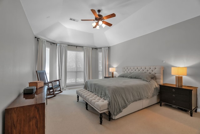 carpeted bedroom with a raised ceiling and ceiling fan