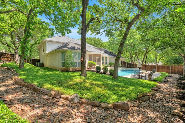 back of property featuring brick siding, central air condition unit, a sunroom, and roof with shingles