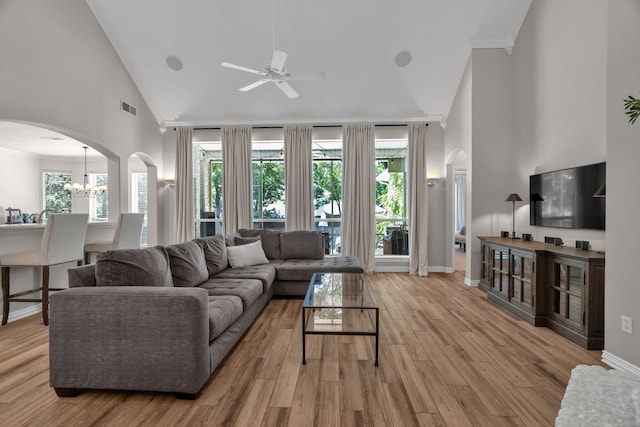 living room featuring high vaulted ceiling, ceiling fan, arched walkways, wood finished floors, and baseboards