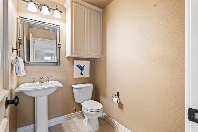 bathroom featuring toilet, tile patterned flooring, baseboards, and a sink