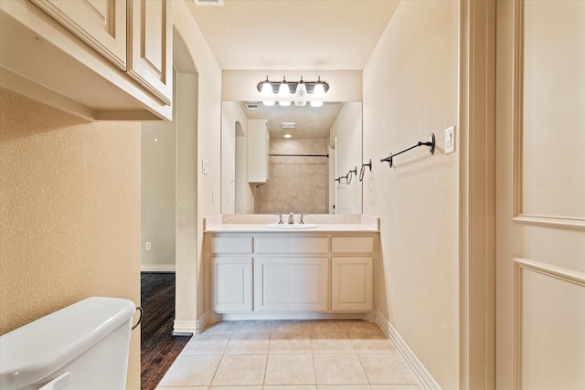 full bathroom featuring toilet, vanity, tile patterned floors, and baseboards