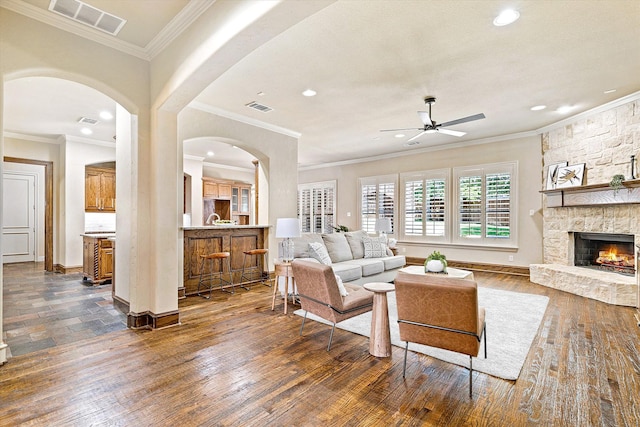 living room featuring a ceiling fan, recessed lighting, arched walkways, a fireplace, and dark wood finished floors