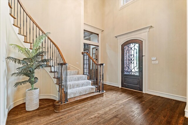 entryway with wood finished floors, a high ceiling, stairs, and baseboards