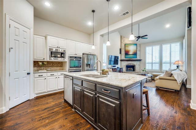 3020 Speyburn, The Colony, TX 75056 - kitchen featuring stainless steel appliances, a sink, a brick fireplace, white cabinetry, and lofted ceiling