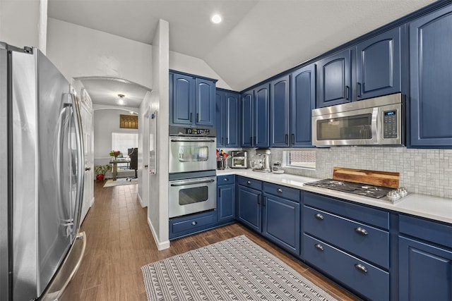 705 Eagle Ct, Mansfield, TX 76063 - kitchen with appliances with stainless steel finishes, blue cabinets, lofted ceiling, light countertops, and tasteful backsplash