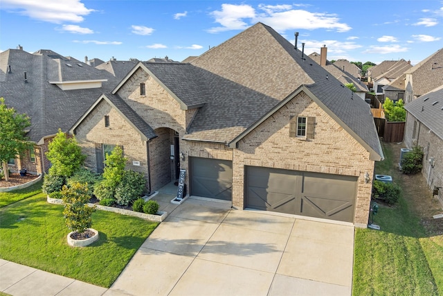 1105 Collared Dove Dr, Little Elm, TX 75068 - french country home featuring a shingled roof, brick siding, concrete driveway, a front yard, and a garage
