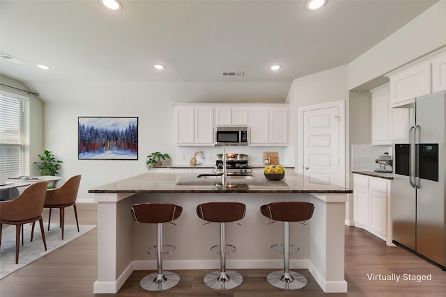 2122 Slow Stream Dr, Royse City, TX 75189 - kitchen with appliances with stainless steel finishes, dark stone countertops, tasteful backsplash, dark wood-style flooring, and a kitchen breakfast bar