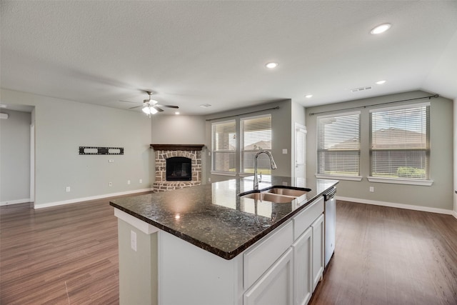 2122 Slow Stream Dr, Royse City, TX 75189 - kitchen with a sink, ceiling fan, dark wood finished floors, white cabinets, and a glass covered fireplace