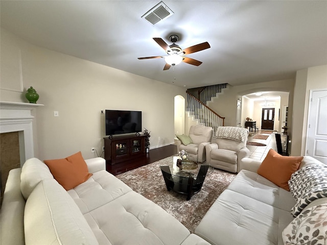 8608 Davis Dr, Frisco, TX 75036 - living room featuring arched walkways, a ceiling fan, wood finished floors, a fireplace, and stairway