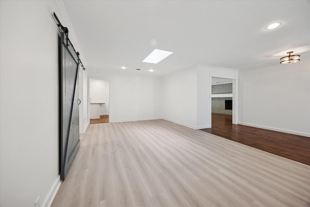 3211 Darby Ln, Denton, TX 76207 - unfurnished room featuring a barn door, light wood finished floors, baseboards, recessed lighting, and a skylight