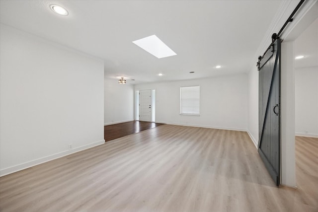 3211 Darby Ln, Denton, TX 76207 - spare room with a barn door, light wood-style flooring, recessed lighting, a skylight, and baseboards