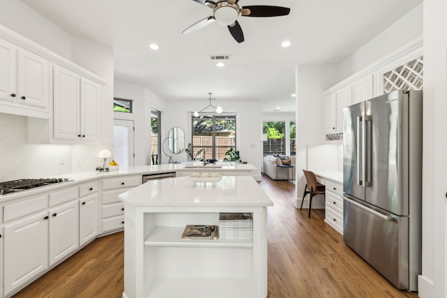 kitchen with stainless steel appliances, a peninsula, white cabinetry, wood finished floors, and recessed lighting