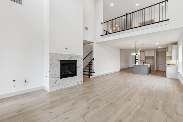 130 Scottish Way, Mansfield, TX 76063 - unfurnished living room with a towering ceiling, stairs, a fireplace, light wood-style flooring, and a chandelier