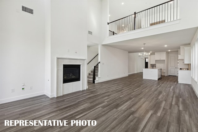 130 Scottish Way, Mansfield, TX 76063 - unfurnished living room featuring a high ceiling, stairway, dark wood-style flooring, a chandelier, and baseboards