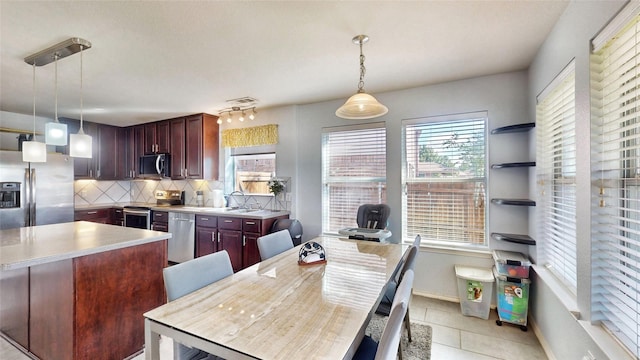 2225 Marion Dr, Mckinney, TX 75072 - kitchen with stainless steel appliances, light countertops, backsplash, light tile patterned floors, and decorative light fixtures