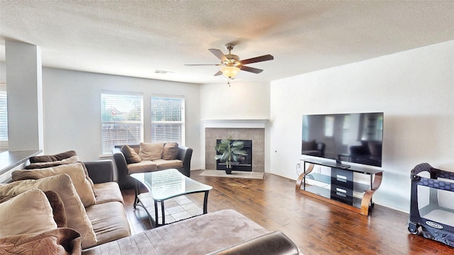 2225 Marion Dr, Mckinney, TX 75072 - living room featuring hardwood / wood-style flooring, a ceiling fan, a fireplace, baseboards, and a textured ceiling