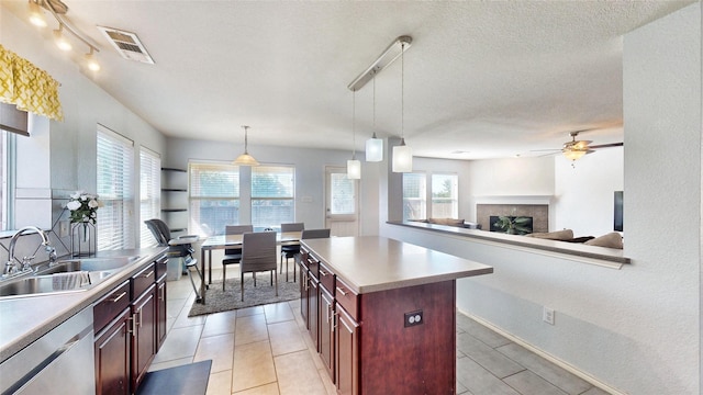 2225 Marion Dr, Mckinney, TX 75072 - kitchen featuring stainless steel dishwasher, a sink, a textured ceiling, a fireplace, and ceiling fan