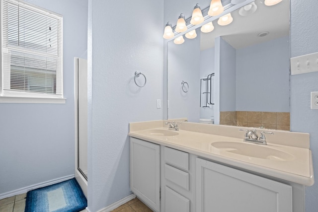 303 Stonegate Blvd, Alvarado, TX 76009 - full bathroom with double vanity, a shower with shower door, baseboards, tile patterned flooring, and a textured wall