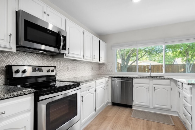 kitchen featuring appliances with stainless steel finishes, a sink, white cabinets, and light wood-type flooring