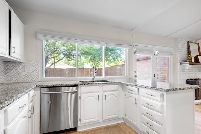 kitchen with stainless steel dishwasher, a sink, white cabinetry, and light stone counters