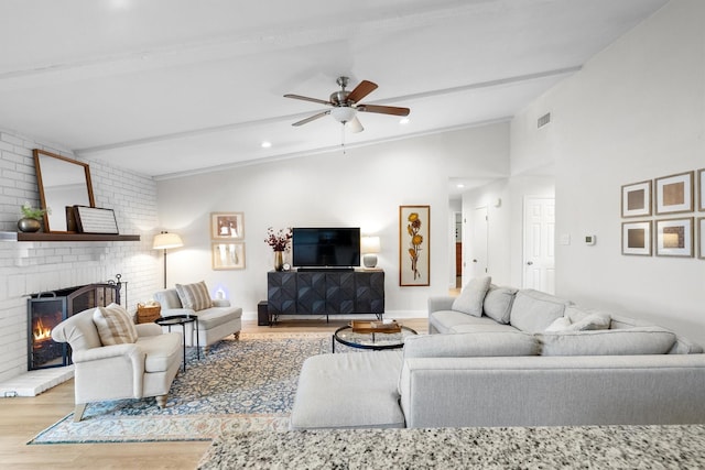 living area with lofted ceiling, wood finished floors, a fireplace, and a ceiling fan