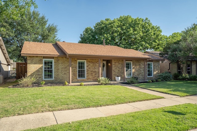 ranch-style house with a front lawn, brick siding, roof with shingles, and central AC unit