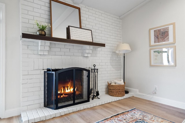 detailed view of a brick fireplace, wood finished floors, and baseboards