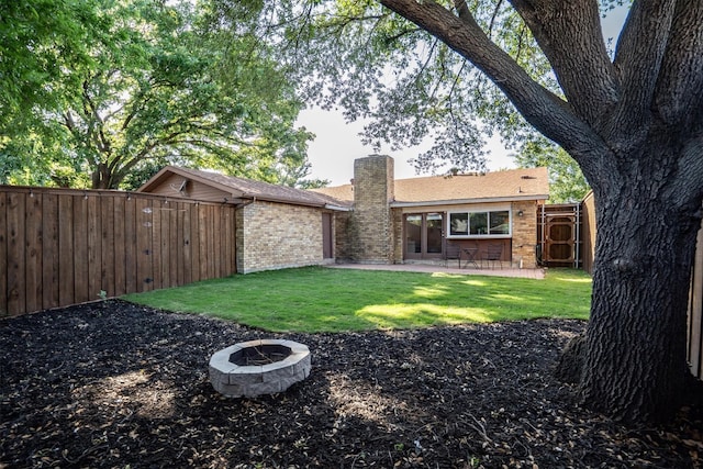 rear view of property with brick siding, a chimney, a patio area, and an outdoor fire pit