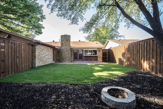 back of property featuring a chimney, brick siding, an outdoor fire pit, and a patio