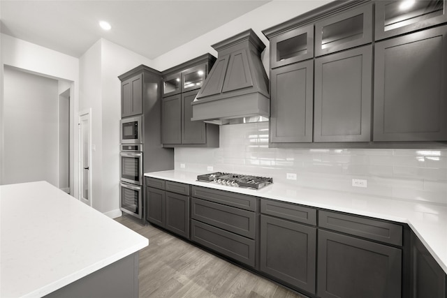 329 Lovett Ln, Burleson, TX 76028 - kitchen featuring custom exhaust hood, light wood finished floors, light countertops, tasteful backsplash, and appliances with stainless steel finishes