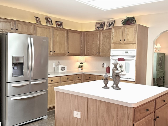 3335 Hedrick Ln, Princeton, TX 75407 - kitchen featuring stainless steel fridge, oven, arched walkways, light countertops, and a center island