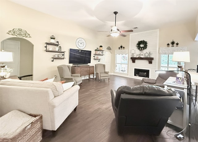 3335 Hedrick Ln, Princeton, TX 75407 - living area featuring arched walkways, dark wood-style flooring, ceiling fan, and a fireplace