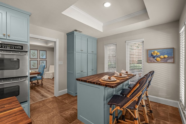 3304 Bowden Hill Ln N, Colleyville, TX 76034 - kitchen featuring butcher block counters, double oven, a tray ceiling, blue cabinets, and crown molding