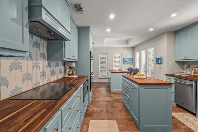 3304 Bowden Hill Ln N, Colleyville, TX 76034 - kitchen featuring wood counters, stainless steel dishwasher, custom exhaust hood, a center island, and blue cabinetry